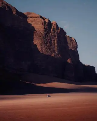 a car in the desert next to a mountain at Bedouin cave wadi rum campsite in Wadi Rum