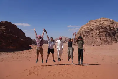 a group of people jumping in the desert at Bedouin cave wadi rum campsite in Wadi Rum