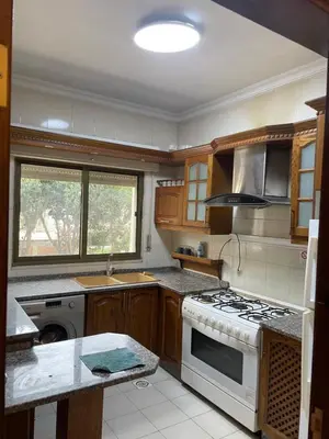 a kitchen with wooden cabinets and a stove top oven at Charming modern 2BD in Abdoun in Amman