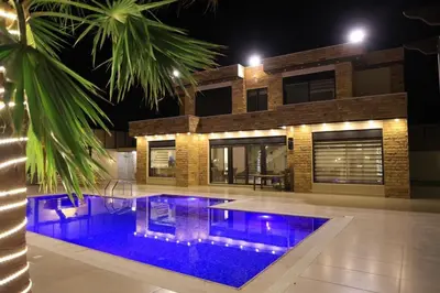 a swimming pool in front of a house at night at Sunrise Villa in Sowayma