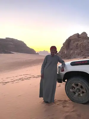 a man standing on the beach next to a truck at Ahmad and Fatima's Traditional Bedouin Camp in Wadi Rum