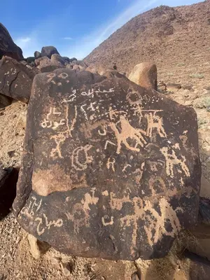 a rock with writing on it with a mountain in the background at Ahmad and Fatima's Traditional Bedouin Camp in Wadi Rum