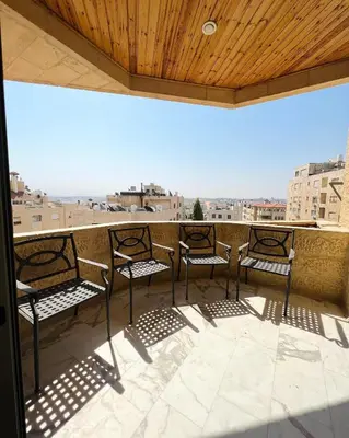 three chairs on a balcony with a view of a city at Furnished Apartment for Rent in Abdoun 200sqm in Amman