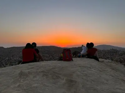 a group of people sitting on top of a mountain watching the sunset at Al -Nawatef Eco Lodge- Dana Nature Reserve in Dana