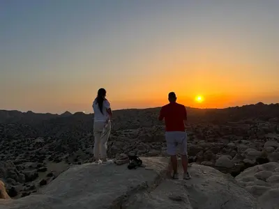 a man and a woman standing on a rock watching the sunset at Al -Nawatef Eco Lodge- Dana Nature Reserve in Dana