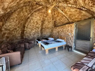 a room with a bed and a couch in a cave at Al -Nawatef Eco Lodge- Dana Nature Reserve in Dana
