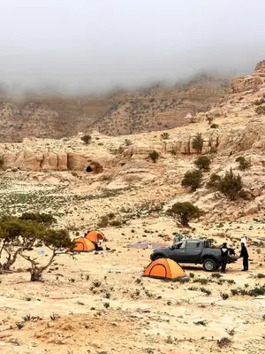 a group of tents and a jeep in the desert at Al -Nawatef Eco Lodge- Dana Nature Reserve in Dana