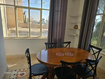 a dining room table and chairs in front of a window at B Beitna in Amman