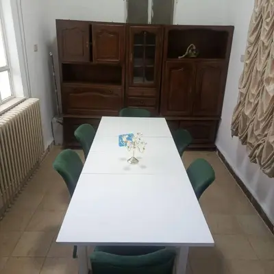 a white table with green chairs in a room at B Beitna in Amman