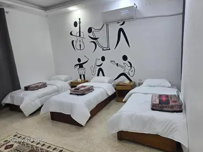 a room with three beds with music on the wall at B Beitna in Amman