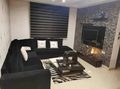 a living room with a black couch and a tv at Apartment in Amman 7'th Circle in Amman