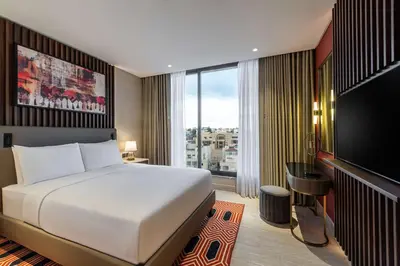 a hotel room with a bed and a large window at Doubletree By Hilton Amman Hotel & Residences in Amman