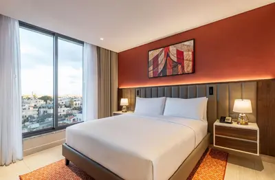 a bedroom with a large bed and a large window at Doubletree By Hilton Amman Hotel & Residences in Amman