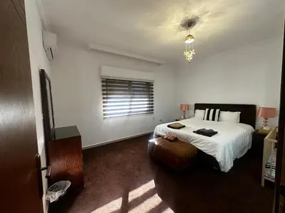 a bedroom with a bed and a chair and a window at 8-New and Spacious Apartments Close to Market in Amman
