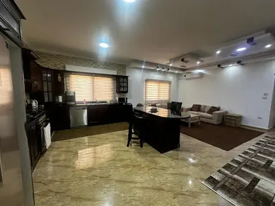 a kitchen and living room with a table and a couch at 8-New and Spacious Apartments Close to Market in Amman