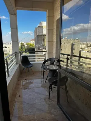 a balcony with chairs and a table and a view of a city at 8-New and Spacious Apartments Close to Market in Amman