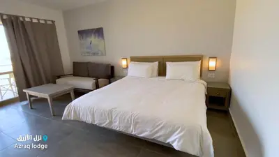 a bedroom with a large white bed and a chair at Azraq Lodge in Al Azraq ash Shamālī