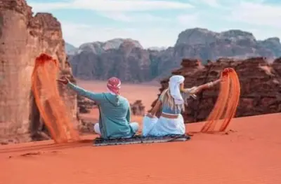 a man and a woman sitting in the desert at Ayman camp in Wadi Rum