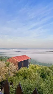 a small house on top of a hill with fog at اكواخ سفاري السياحية in Ajloun