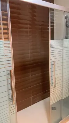 a glass shower with wooden blinds in a bathroom at Rooftop View in Amman