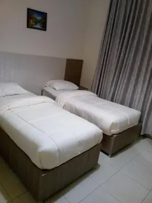 two beds in a hotel room with white sheets at في ظلال الطبيعه in Aqaba
