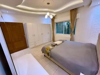 a bedroom with a bed and a large window at Fully Equipped 3BR Apt in Family-Friendly Building in Amman