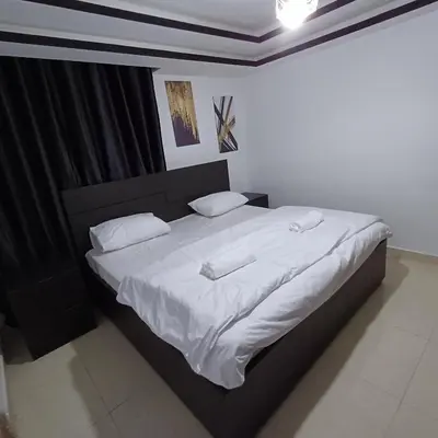 a bedroom with a large bed with white sheets and pillows at Laperla luxury family apartment one in Amman