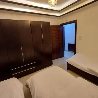 a bedroom with two beds and a cabinet and a window at Laperla luxury family apartment one in Amman