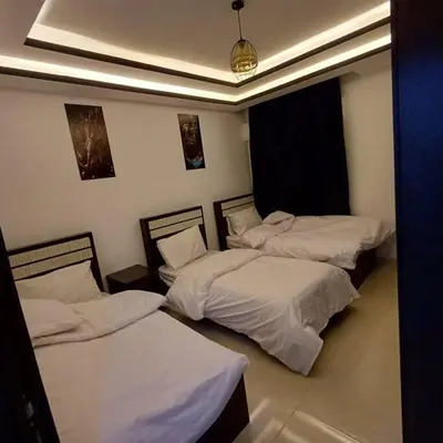 two beds in a room with white sheets at Laperla luxury family apartment one in Amman