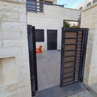 an open door to a patio with a chair at Laperla luxury family apartment one in Amman