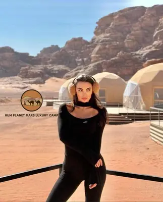 a woman in a black dress standing in the desert at RUM BUBBLES VIEW lUXURY CAMP in Wadi Rum