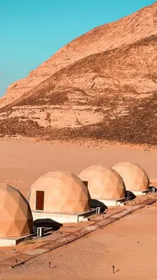 a row of tents in a desert with a hill at RUM MARS lUXURY SANDS BUBBLE CAMP in Wadi Rum