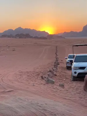 two trucks parked in the desert with the sunset in the background at Desert Magic Camp in Wadi Rum