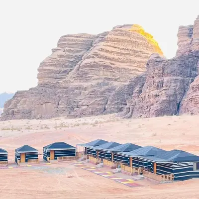 a group of blue tents in the desert with a mountain at wadi Rum Mohammed in Wadi Rum