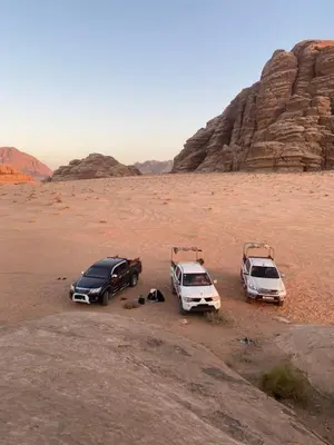 three cars are parked in the desert at Wadi Rum Red Desert in Wadi Rum