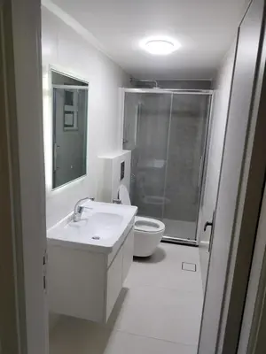a white bathroom with a sink and a toilet at Amman Sweet-Home - 2 bedrooms Apartment in Amman