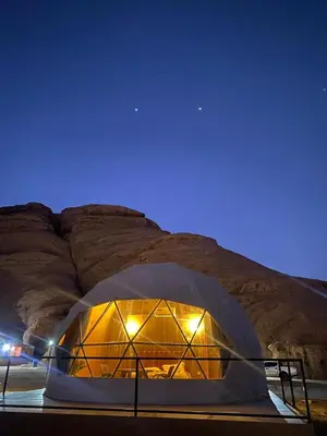 a dome tent with lights in front of a mountain at Sela wadi rum in Wadi Rum