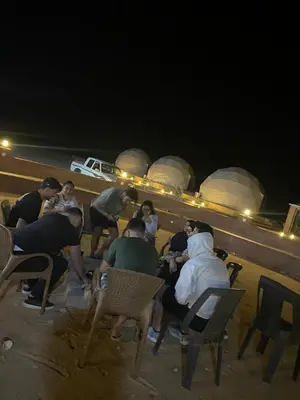 a group of people sitting in chairs on the beach at night at Sela wadi rum in Wadi Rum