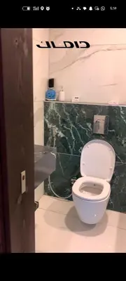a bathroom with a white toilet and a green wall at شقه دوبلكس داماك العبدلي in Amman