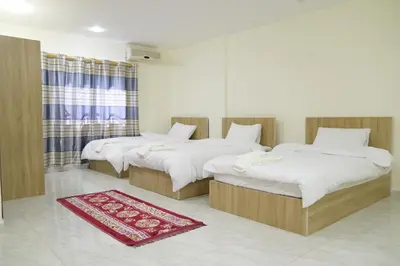 two beds in a room with a red rug at Uncle Ali hotel in Wadi Musa