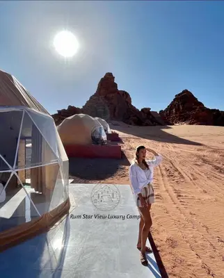 a woman standing next to a tent in the desert at RUM STAR VIEW BUBBLES lUXURY CAMP in Wadi Rum