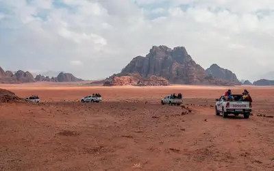 a group of people in trucks driving through the desert at Wadi rum camp with tour in Wadi Rum