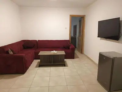 a living room with a red couch and a tv at Ryan Hotel Suites in Amman