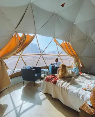a woman sitting on a bed in a tent at RUM HiLTON lUXURY CAMP in Wadi Rum