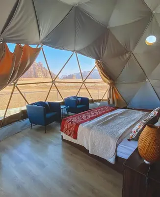 a bedroom with a bed and chairs in a tent at RUM HiLTON lUXURY CAMP in Wadi Rum