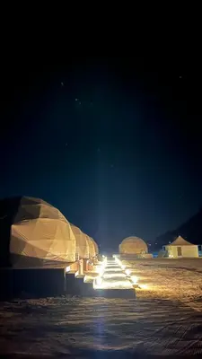 a row of tents on a beach at night at RUM HiLTON lUXURY CAMP in Wadi Rum