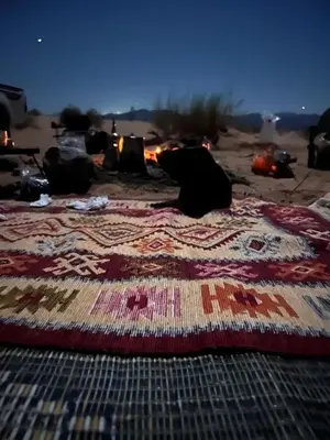 a quilt laying on the sand on the beach at Nora Bedouin Home in Petra