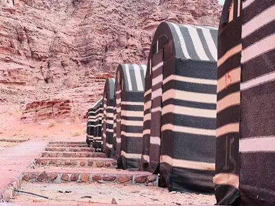 a row of large trucks parked in the desert at Desert Rock Wadi Rum in Wadi Rum