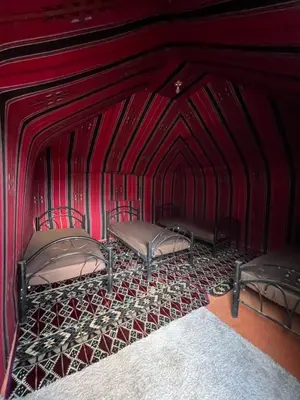 two beds in a room with red walls at Desert Rock Wadi Rum in Wadi Rum