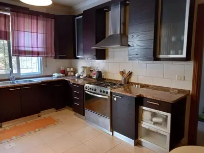 a kitchen with black cabinets and a stove top oven at Happy Family Home with Spacious Garden in Amman